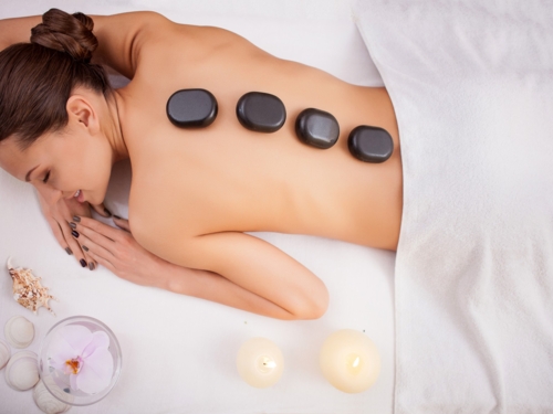 wellness_massage_lava_stone_brunette_flower_candle_image_sh_331039487